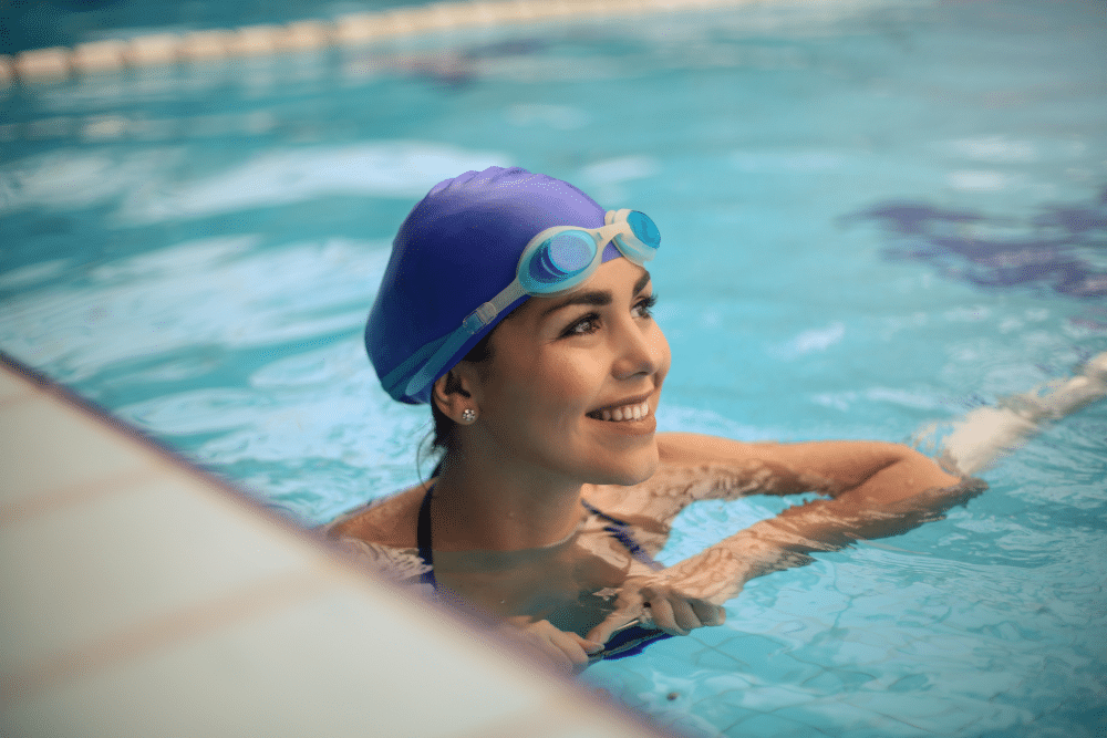 Eine Schwimmerin im Freibad trägt Schwimmbrille und Badekappe