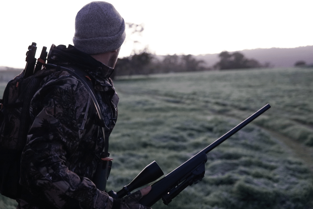 Ein Jäger steht auf freiem Feld mit einem Gewehr in der Hand